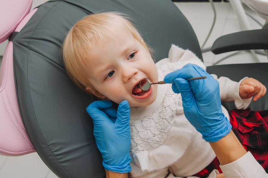 The dentist examines the child's teeth in the dental chair.