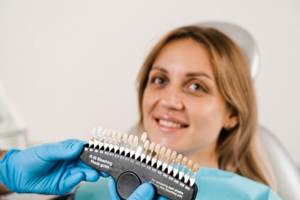 woman in a dentist chair and the dentist is holding a tooth colour shade 