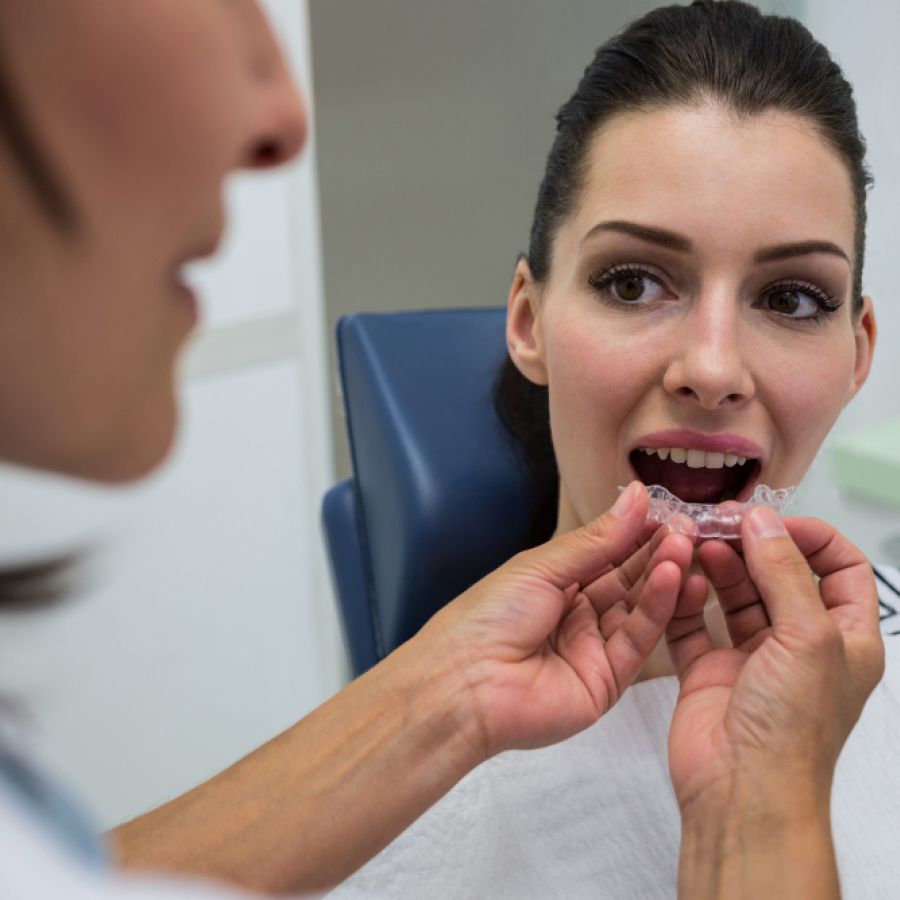 Dentist assisting a patient to wear invisible braces
